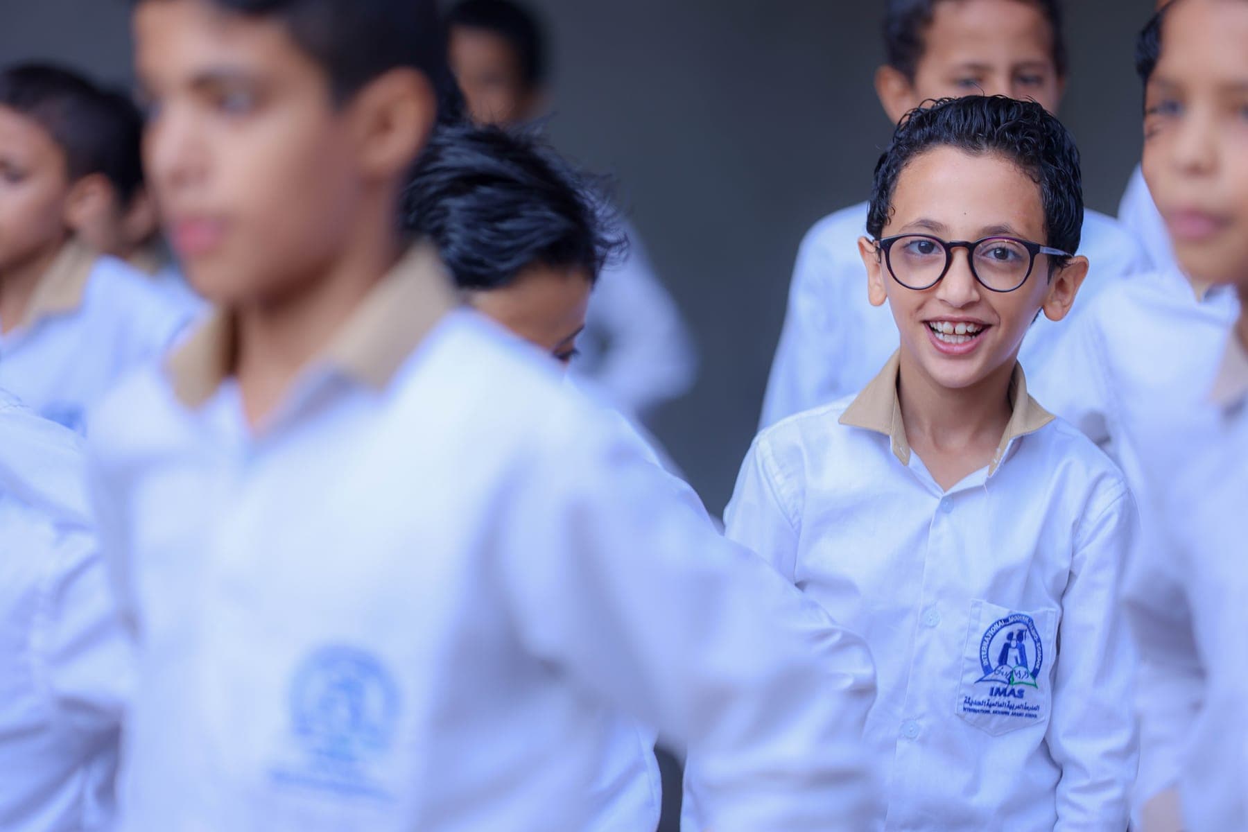 A smiling schoolboy in uniform among classmates at a school in Yemen